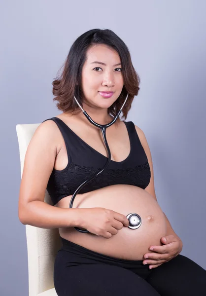 Jovem grávida asiático mulher com estetoscópio ouvindo barriga para b — Fotografia de Stock