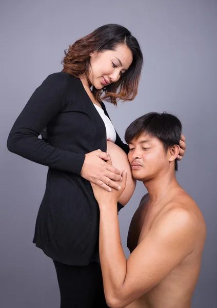 Jovem casal: mãe grávida e pai feliz no backgroun cinza — Fotografia de Stock