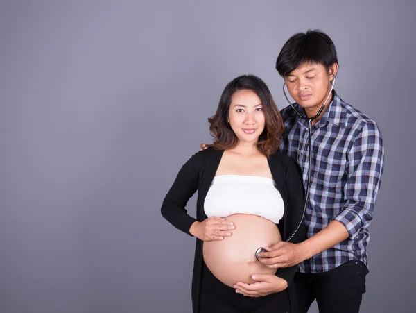 Ember figyel a hasa, terhes felesége sztetoszkóp — Stock Fotó