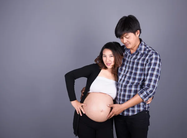 Giovane coppia: madre incinta e padre felice su backgroun grigio — Foto Stock