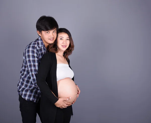 对年轻的夫妇︰ 怀孕的母亲和快乐的父亲在灰色背景 — 图库照片