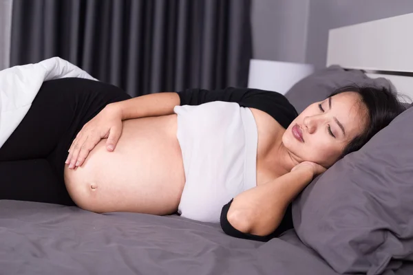 Schwangere schläft auf Bett im Schlafzimmer — Stockfoto