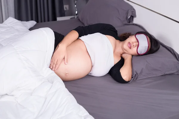 Schwangere schläft auf Bett im Schlafzimmer — Stockfoto