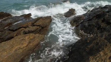 Deniz dalgaları kayalara çarpıyor ve su sıçrıyor