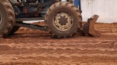 Traktör kırmızı bir toprak sürüyor.