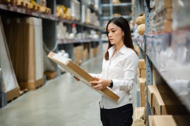 Depodaki envanteri kontrol eden genç bir kadın işçi.