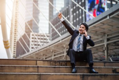 Başarılı bir iş adamı şehirde eli kolu havada bir cep telefonuyla konuşuyor.