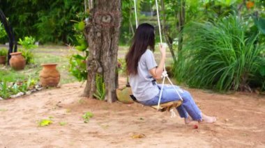 Kadın bahçede salıncakta sallanıyor.