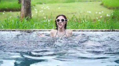 Havuzda yüzen ve su sıçratan bir kadın.