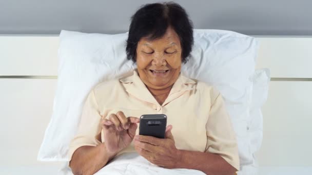 Gelukkig Senior Vrouw Met Behulp Van Mobiele Telefoon Een Bed — Stockvideo