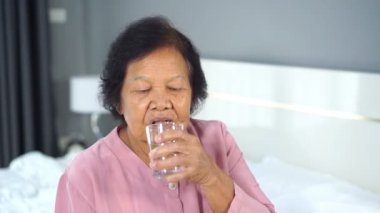 Yatak odasında su içen yaşlı bir kadının ağır çekimde