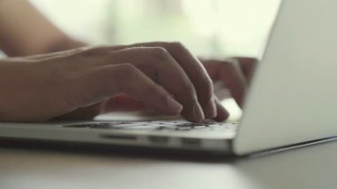 Masadaki dizüstü bilgisayarın klavyesinde çalışan ve daktilo eden ellerin kapatılması 