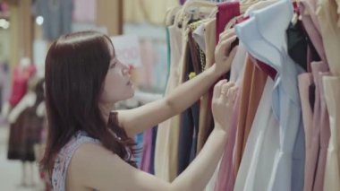 Genç bir kadın giyim mağazasından alışveriş yapıyor.
