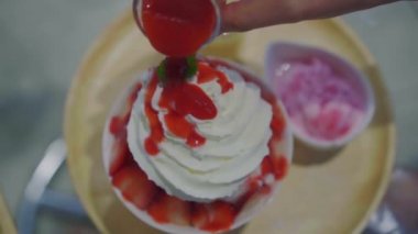 Taze süt aromalı çilekli bingsu ya da buzlu buzun üstüne sos dökmek.