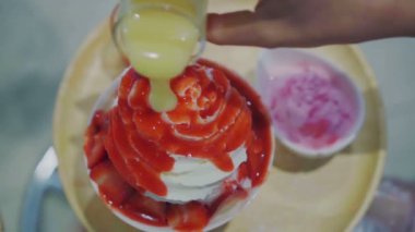 Taze süt aromalı çilekli bingsu ya da buzlu buzun üstüne sos dökmek.