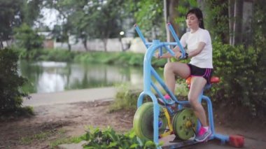 Park 'ta egzersiz bisikletine binen bir kadının ağır çekimde