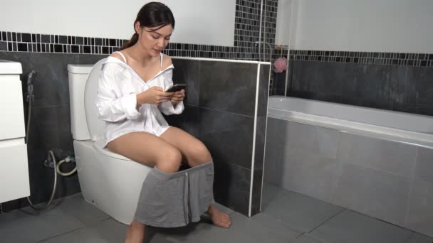 Kvinna Som Använder Mobiltelefon Och Sitter Toaletten Badrummet — Stockvideo