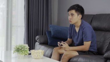 Üzgün genç adam video oyunları oynuyor ve kaybediyor.