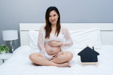 Yatağında boş tabela olan hamile bir kadın.