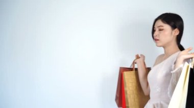 Yavaş çekimde yürüyen ve elinde alışveriş çantası tutan mutlu bir kadın.