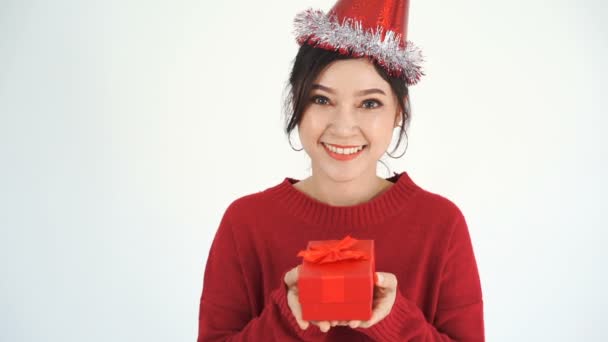 帽子をかぶった幸せな若い女性のスローモーションと与えることのジェスチャーで赤いクリスマスのギフトボックスを保持 — ストック動画