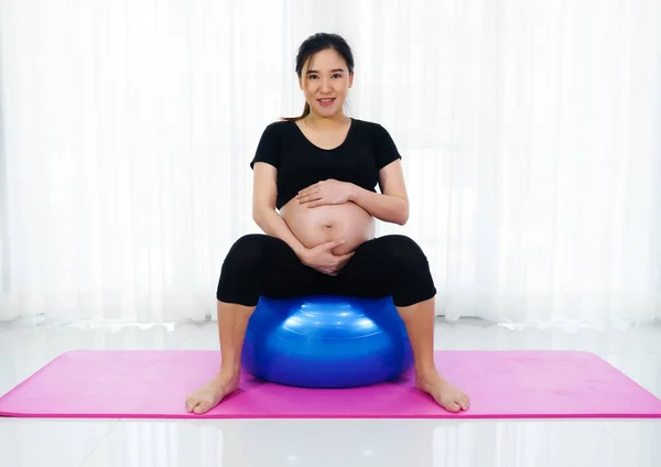 孕妇在家里客厅的健身球上做瑜伽运动 — 图库照片
