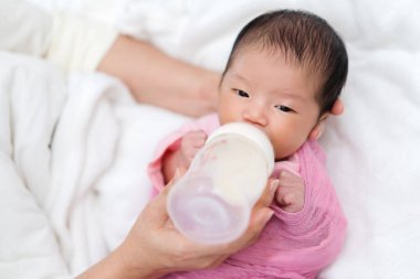 Anne yeni doğmuş bebeğini yatakta emziriyor.