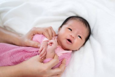 Mutlu yeni doğmuş bebek battaniyeye sarılmış ve ebeveyn elleri yatağın üzerinde