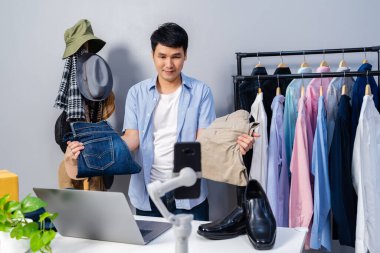 Genç adam online kıyafet ve aksesuar satıyor. Akıllı telefonlardan canlı yayın yapıyor. Evdeki internet üzerinden ticaret yapıyor.