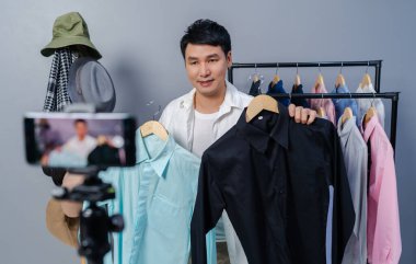 Genç adam online kıyafet ve aksesuar satıyor. Akıllı telefonlardan canlı yayın yapıyor. Evdeki internet üzerinden ticaret yapıyor.