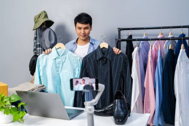 Genç adam online kıyafet ve aksesuar satıyor. Akıllı telefonlardan canlı yayın yapıyor. Evdeki internet üzerinden ticaret yapıyor.