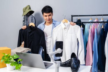 Genç adam online kıyafet ve aksesuar satıyor. Akıllı telefonlardan canlı yayın yapıyor. Evdeki internet üzerinden ticaret yapıyor.