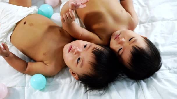 快乐的双胞胎婴儿在床上玩彩球 — 图库视频影像