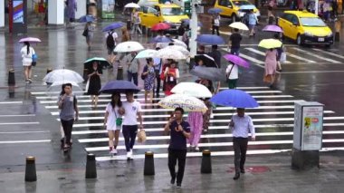 Taipei, Tayvan... 11 Haziran 2019: Tayvan 'ın Taipei şehrinde yağmur yağarken Ximending Alışveriş Bölgesi' nin önünden geçen insanların ağır çekimde görülmesi. Ximending, Taipei 'deki ünlü moda, gece pazarı ve sokak yemeğidir..
