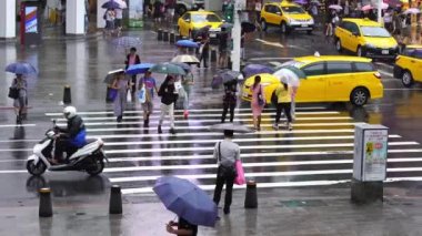 Tayvan, Tayvan. 11 Haziran 2019. İnsanlar Tayvan 'ın Taipei şehrinde yağan yağmurla Ximending Alışveriş Bölgesi önünde karşıdan karşıya geçiyorlar. Ximending, Taipei 'deki ünlü moda, gece pazarı ve sokak yemeğidir..