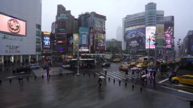 Tayvan, Tayvan. 11 Haziran 2019. İnsanlar Tayvan 'ın Taipei şehrinde yağan yağmurla Ximending Alışveriş Bölgesi önünde karşıdan karşıya geçiyorlar. Ximending, Taipei 'deki ünlü moda, gece pazarı ve sokak yemeğidir..