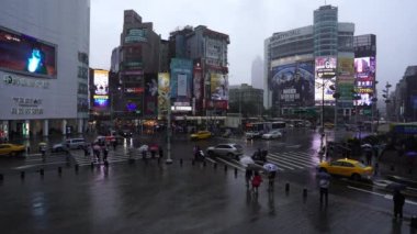 Tayvan, Tayvan. 11 Haziran 2019. İnsanlar Tayvan 'ın Taipei şehrinde yağan yağmurla Ximending Alışveriş Bölgesi önünde karşıdan karşıya geçiyorlar. Ximending, Taipei 'deki ünlü moda, gece pazarı ve sokak yemeğidir..