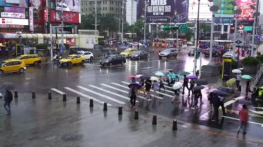 Tayvan, Tayvan. 11 Haziran 2019. İnsanlar Tayvan 'ın Taipei şehrinde yağan yağmurla Ximending Alışveriş Bölgesi önünde karşıdan karşıya geçiyorlar. Ximending, Taipei 'deki ünlü moda, gece pazarı ve sokak yemeğidir..