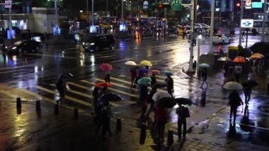 Taipei, Tayvan... 11 Haziran 2019: Tayvan 'ın Taipei şehrinde gece yağmur yağarken Ximending Alışveriş Bölgesi önünde karşıdan karşıya geçen insanlar. Ximending, Taipei 'deki ünlü moda, gece pazarı ve sokak yemeğidir..