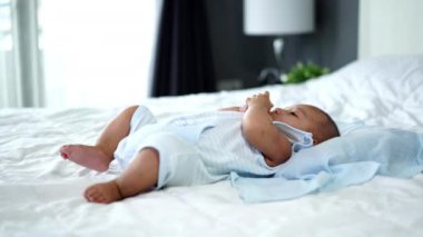 Küçük neşeli bebek, ellerini ve bacaklarını bir yatakta oynat.