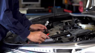 Tamirciler araba servisindeki elektrikli kablo sistemini elle kontrol ediyorlar.