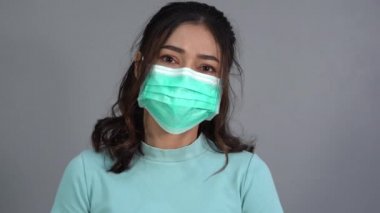 woman in a medical mask(surgical mask) holding alcohol gel with middle finger fuck sign hand gesture, coronavirus protection