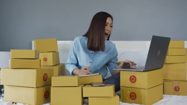 成功した女性はノートパソコンを使って自宅のベッドで製品をオンラインで販売し — ストック動画