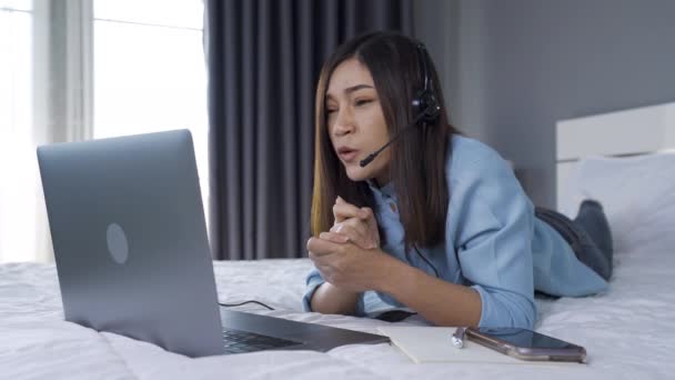 压力大的女商人穿着耳机视频会议 在床上用笔记本电脑打电话 从家里的概念开始工作 — 图库视频影像