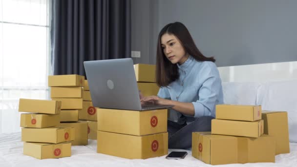 自宅のベッドでノートパソコンを使ってオンラインで製品を販売している若い女性は — ストック動画