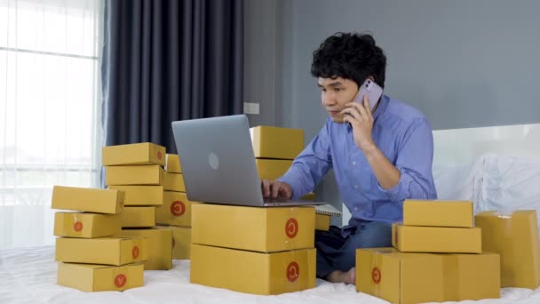 Młody Człowiek Mówi Smartfonie Pomocą Laptopa Sprzedaży Produktu Online Łóżku — Wideo stockowe