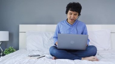 İş adamı kulaklık takıyor. Ev konseptinden çalışmak için laptoptan bilgisayara arıyor.