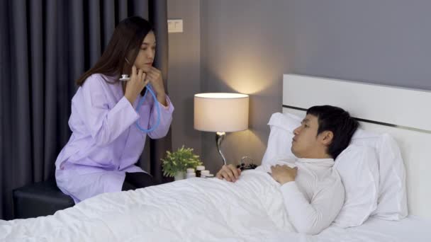 医者は聴診器を使ってベッドの上で男性患者の心臓を聞き — ストック動画