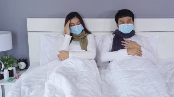ウイルス病と熱に苦しむ医療用マスクの病気カップルInベッド コロナウイルス Covid パンデミックの概念 — ストック動画