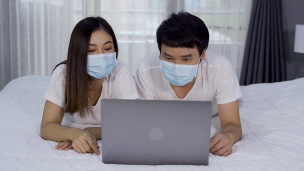 Paar Mit Medizinischen Masken Mit Laptop Auf Einem Bett Während — Stockvideo